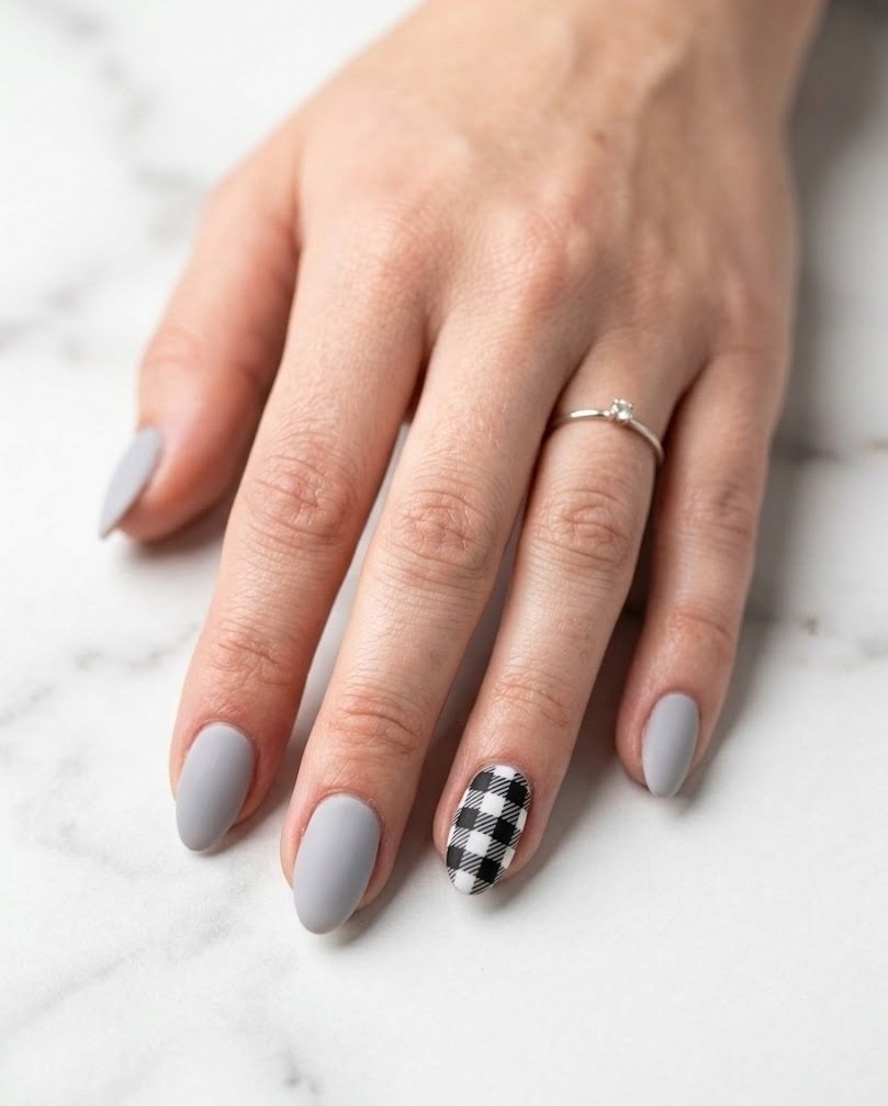Short almond nails with one black and white buffalo check accent and dove gray nails
