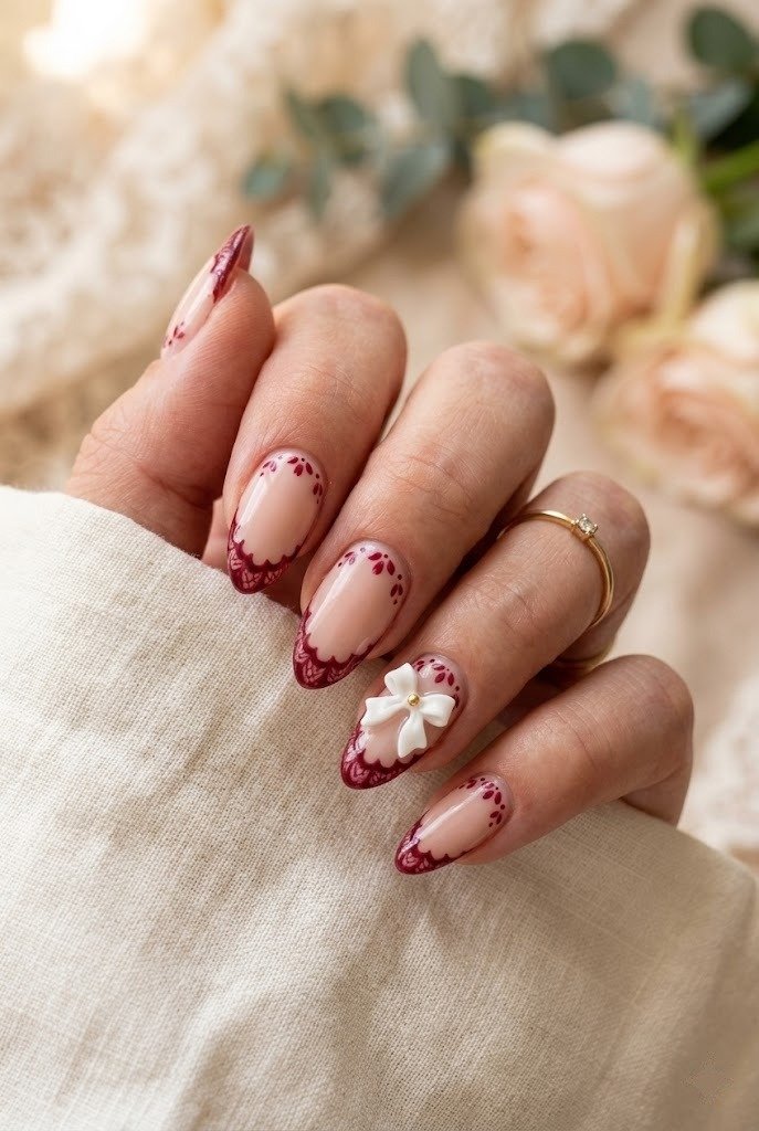 Burgundy lace French tips with petals and a bow accent nail