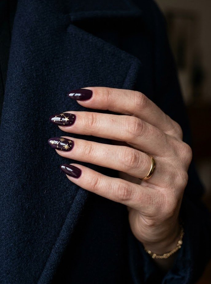 Gold star celestial art on dark plum almond nails
