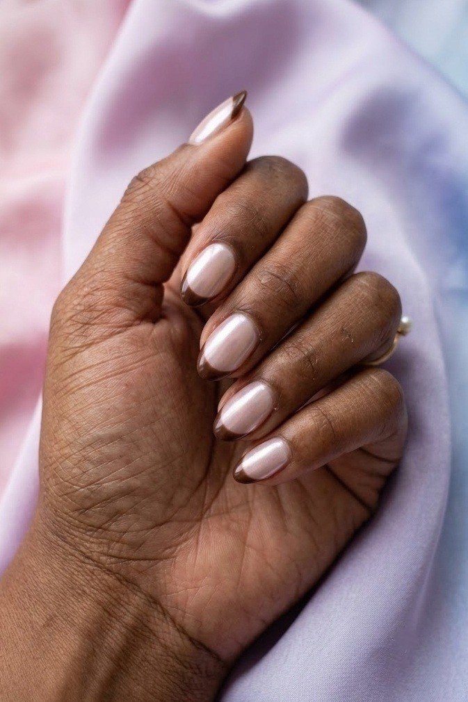 Copper chrome micro French tip over warm brown base on short almond nails