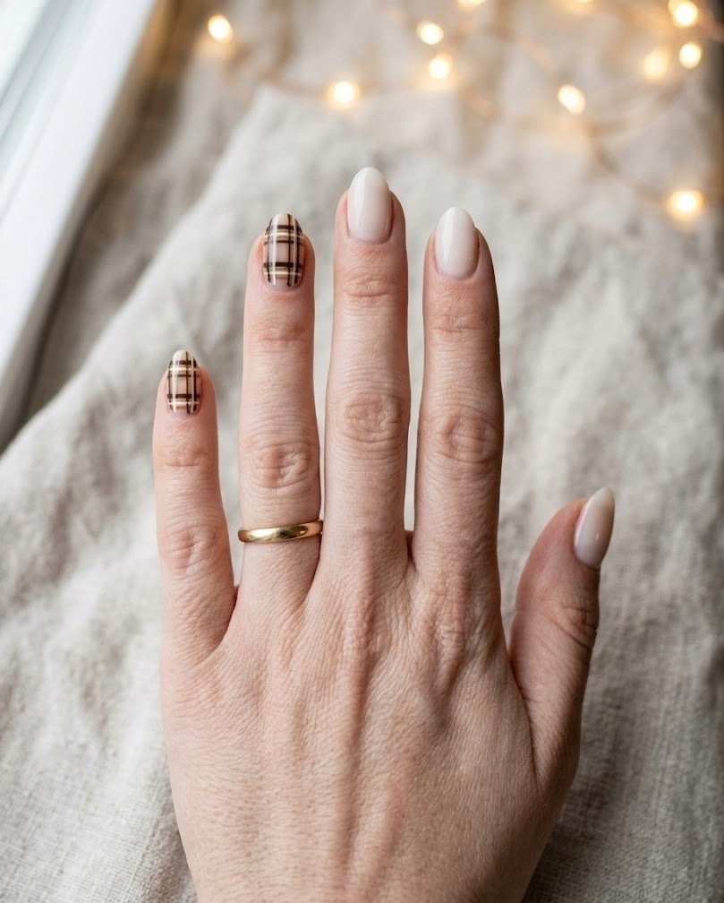 Short almond nails with espresso and cream plaid over a milky jelly base