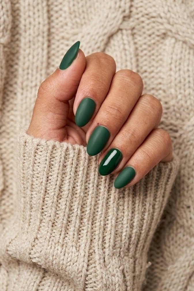 Matte forest green short almond nails with the ring finger left glossy for contrast.