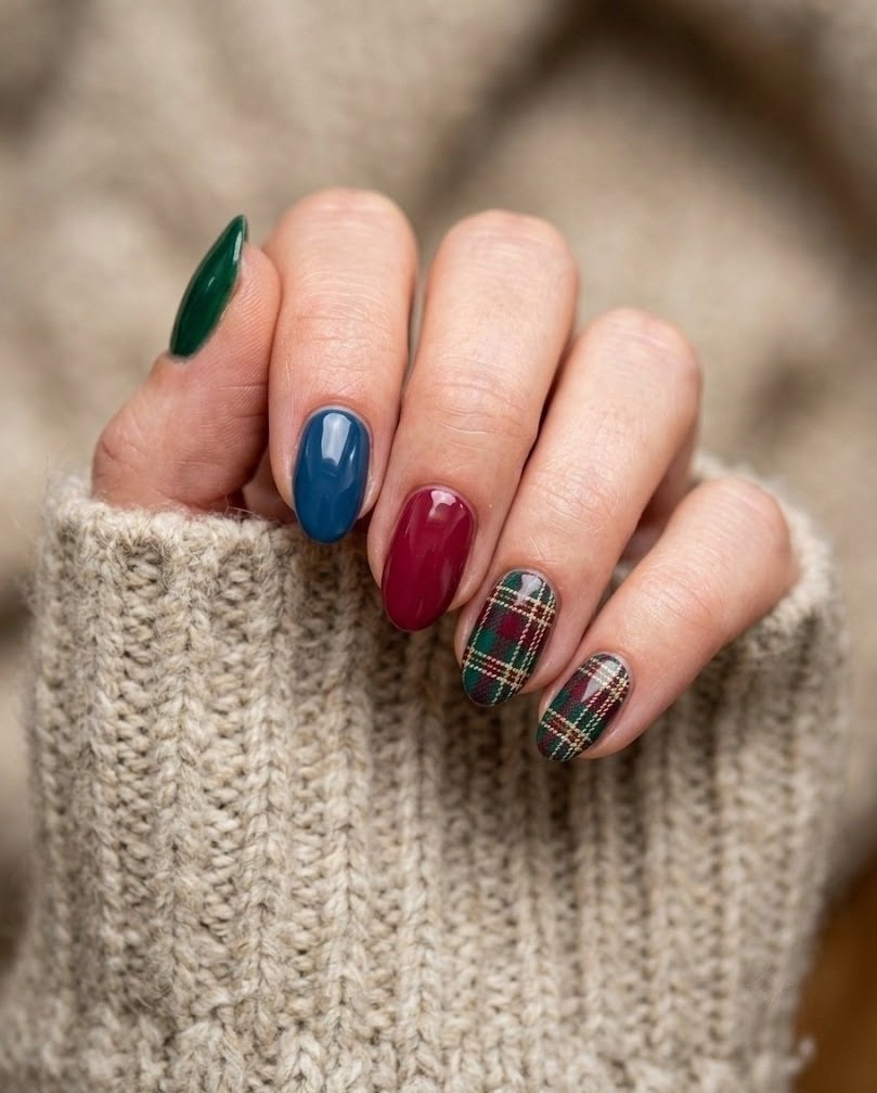 Short almond nails in mixed fall jewel tones with emerald and berry tartan on two nails