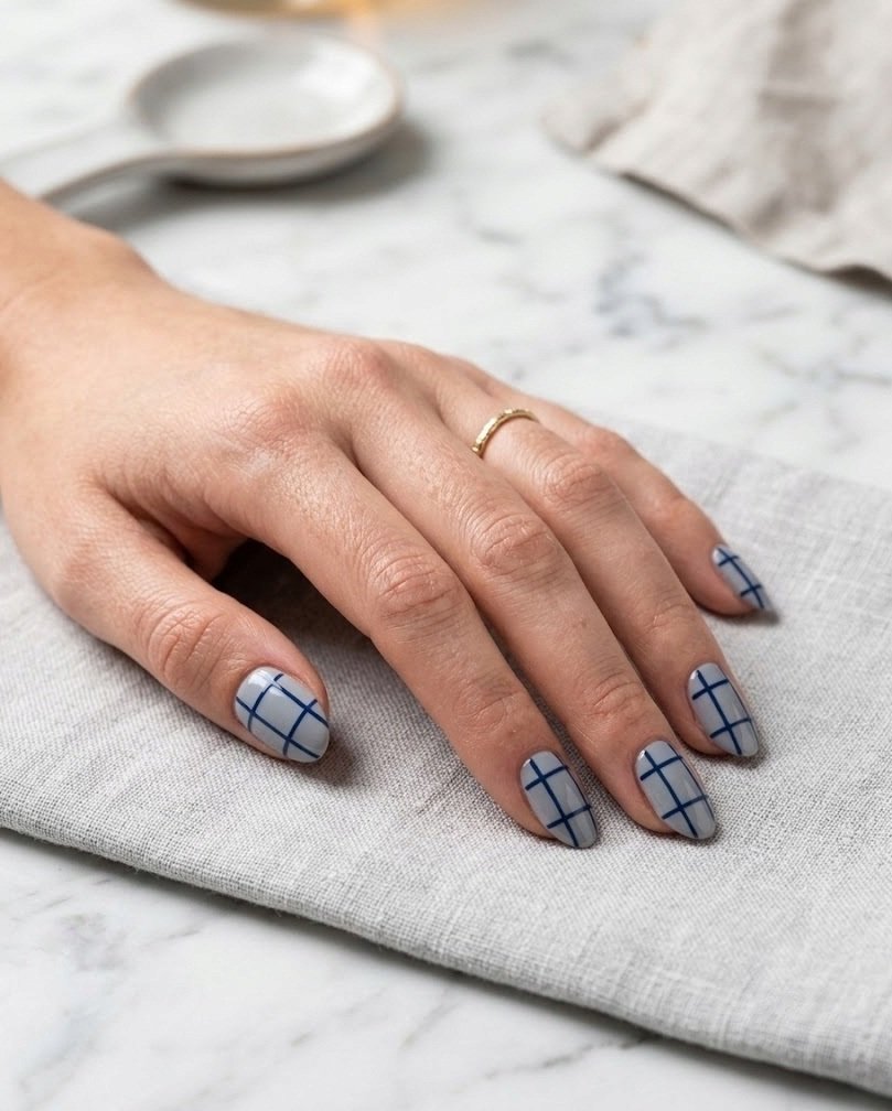 Short almond nails with a single line navy windowpane grid on cool gray