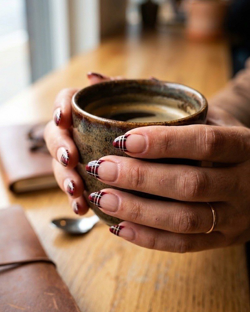 Short almond nails with plaid French tips in red, black and white over a nude base