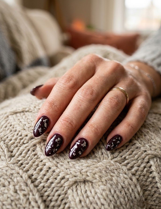 Silver metallic flakes over dark plum polish on almond nails
