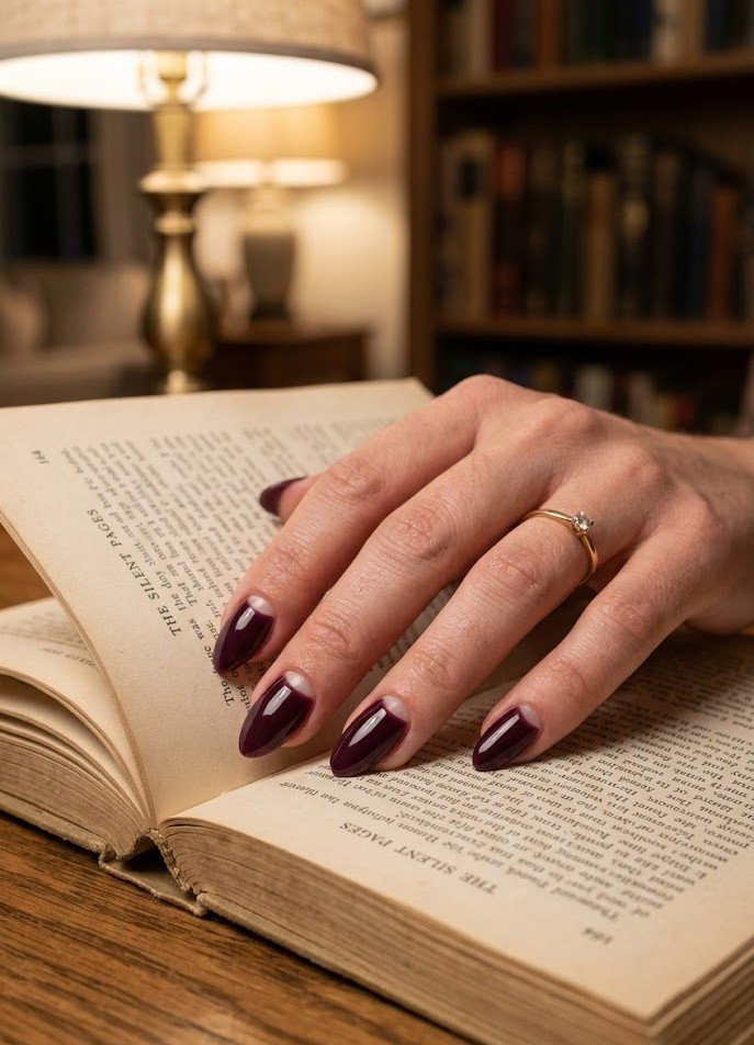 Reverse French half-moon manicure in dark plum on almond nails
