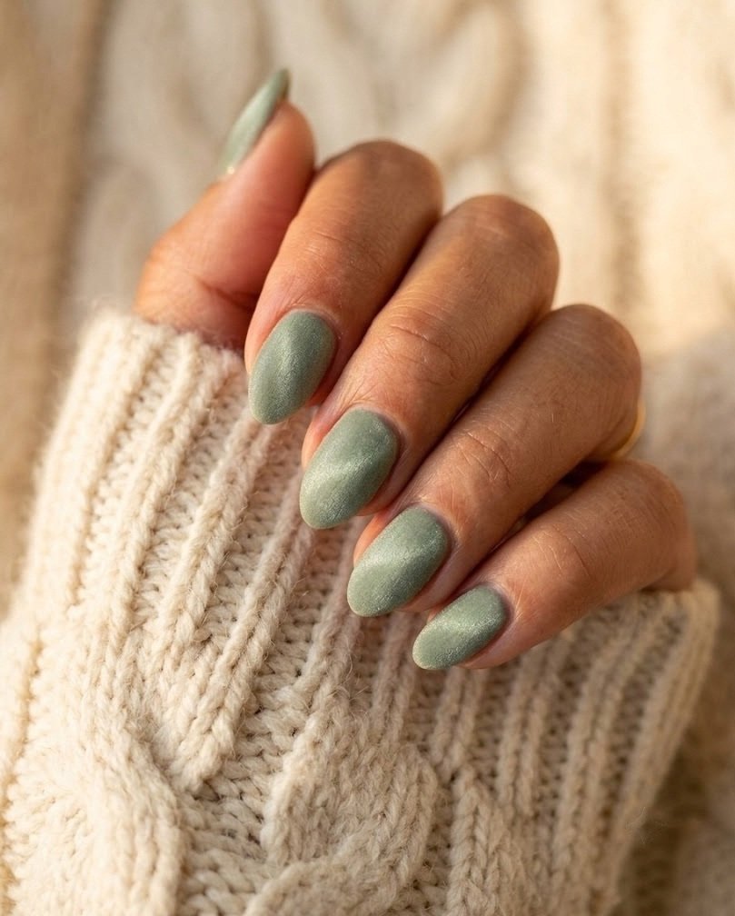 Short almond nails in matte magnetic sage velvet on a tan skin tone hand