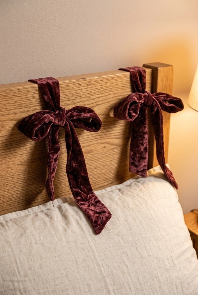 Burgundy velvet ribbon tied in bows on the corners of a wooden headboard