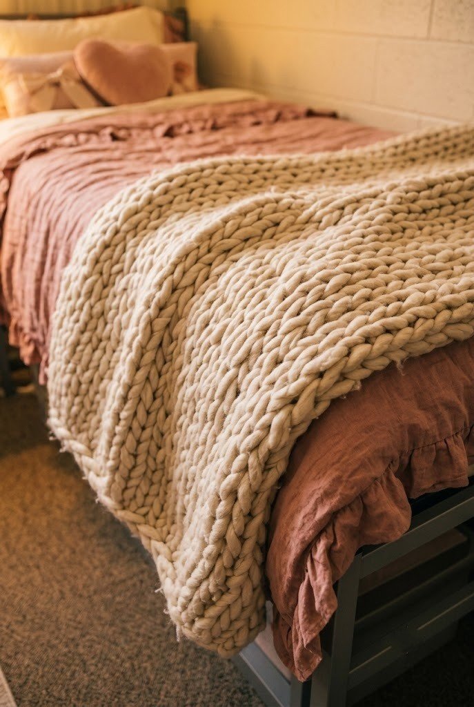 chunky cream knit throw draped across the foot of a dorm bed