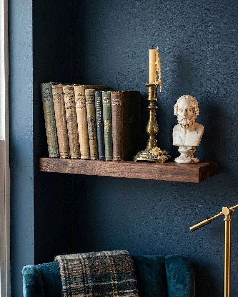 Dark wood no-drill floating shelf with vintage books, a brass candlestick, and a small bust