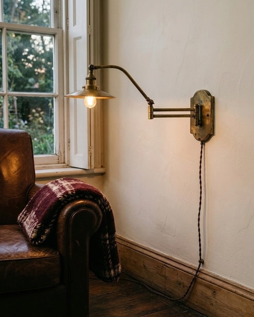 Brass plug-in swing-arm sconce beside a reading chair, arm extended over the seat