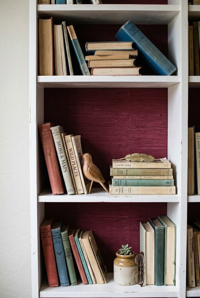 Removable burgundy wallpaper lining the back panel of a white bookshelf
