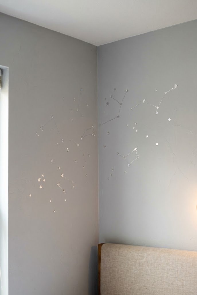 Sparse silver leaf constellation decals in the upper corner of a pale gray bedroom wall