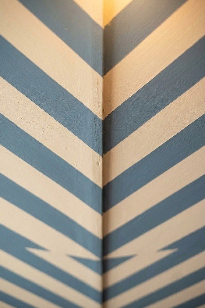 Cream and dusty blue chevron ceiling stripes meeting in a soft V down the center line