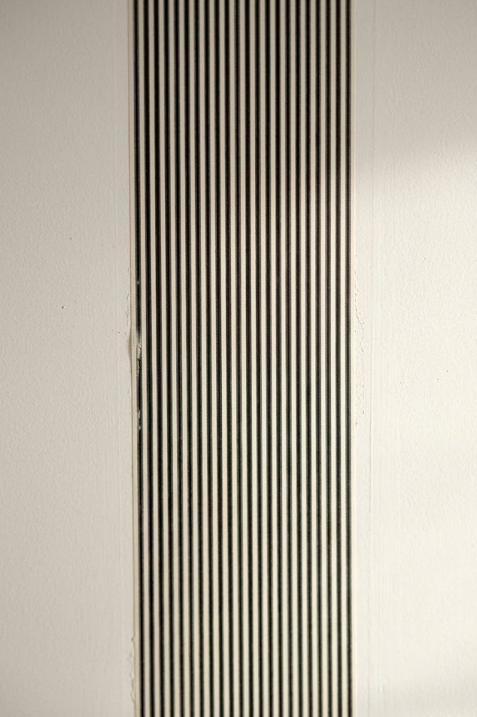 A single strip of black and cream removable striped wallpaper running down the center of a ceiling