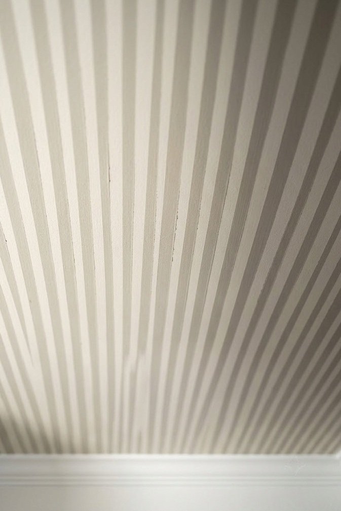Closely spaced low contrast cream and greige ceiling pinstripes about two inches wide