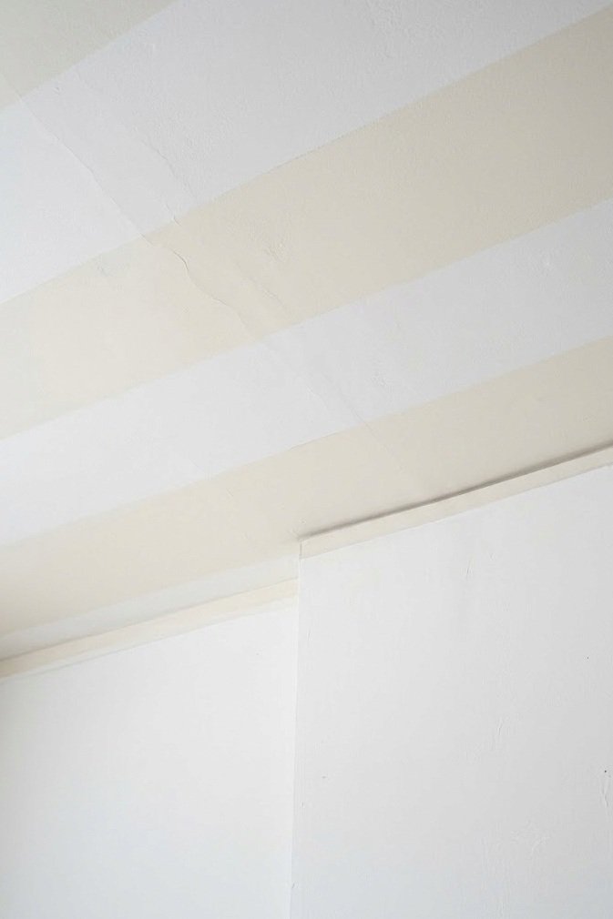 Very low contrast wide horizontal stripes in white and off-white on a bedroom ceiling