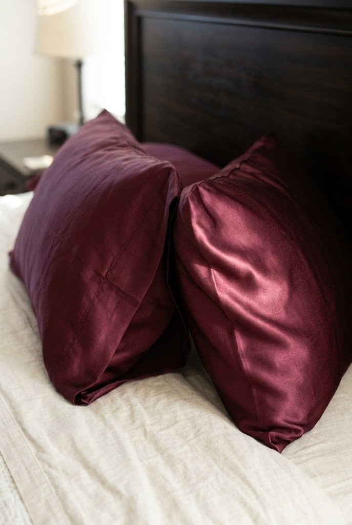 Wine colored satin pillowcases catching morning light
