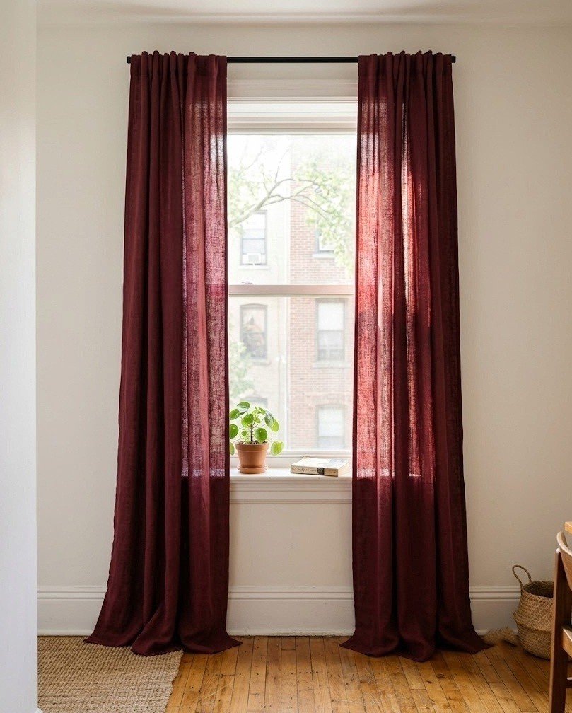 Floor-length wine burgundy curtains on a slim black no-drill rod over an apartment window